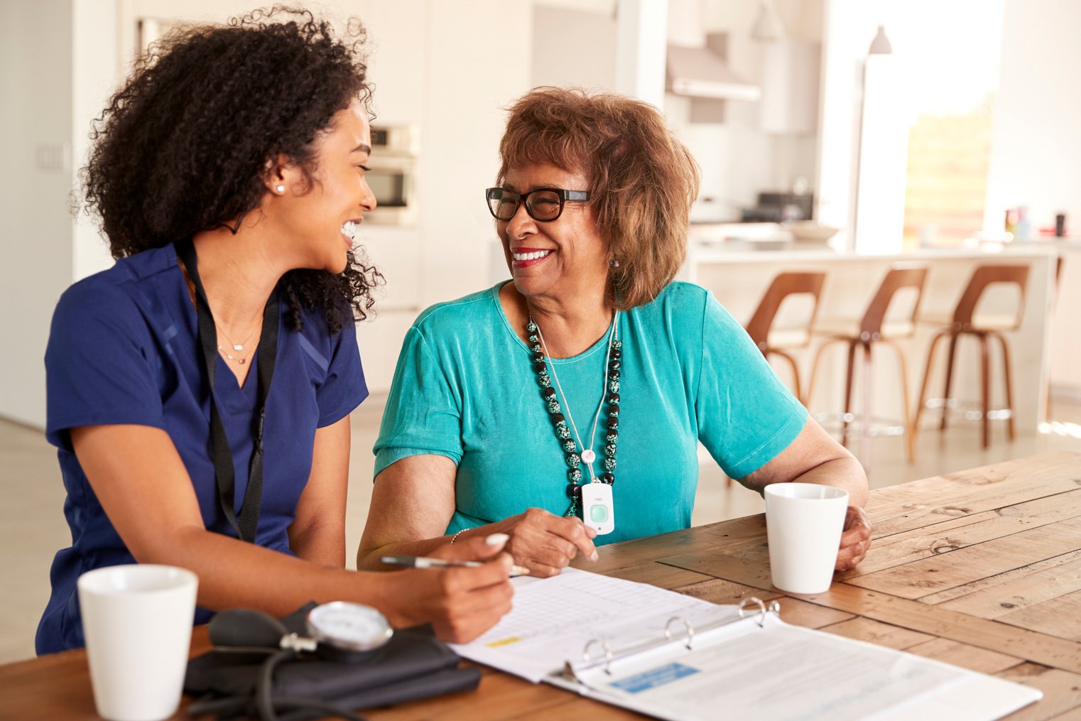 Female Healthcare Worker Sitting at Table Smiling with a Senior